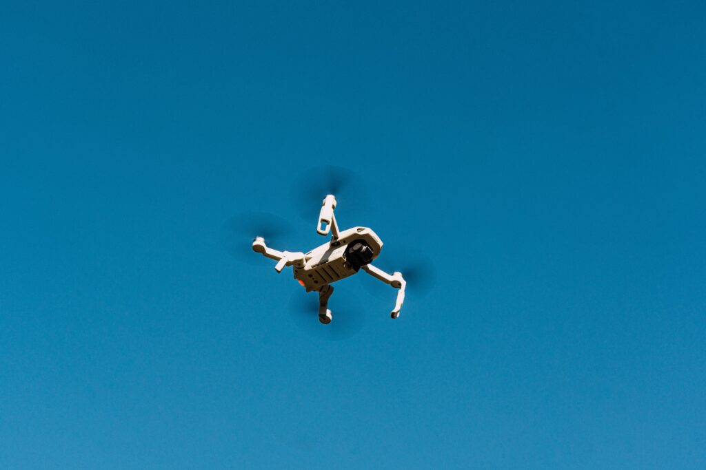 A drone flying against a clear blue sky, capturing aerial views.