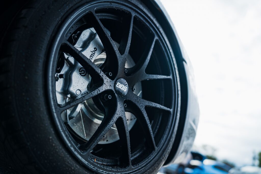Detailed close-up of BBS car wheel showcasing Brembo brakes, outdoors in a rainy setting.